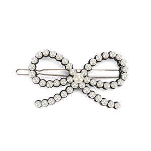 Détail d'une pince à cheveux nœud noir avec perles blanches sur barrette argentée