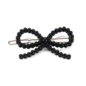 Détail d'une pince à cheveux avec nœud en perles noires sur une barrette en métal argenté