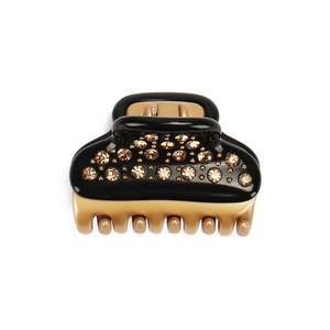 Detail of black acetate hair claw clip with hand-set champagne rhinestones and gold teeth