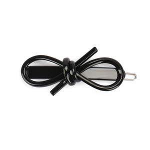 Detail view of glossy black acetate bow hair clip with high-shine finish and metal base
