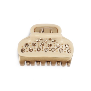 Close-up of beige hair claw clip with sparkling champagne rhinestones and golden teeth