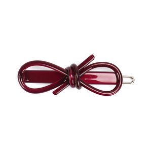 Detail shot of a deep wine red glossy bow hair clip with polished resin finish