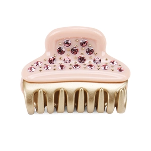 Close-up of pink acetate hair claw clip with sparkling crystals and golden metal teeth