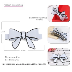 White acrylic bow hair clip with black edges featuring minimalist monochrome design