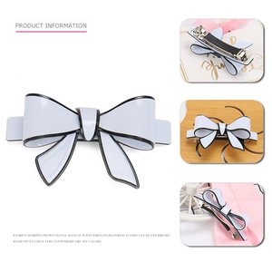 Large white acrylic bow hair clip with black edges and metal spring fastener