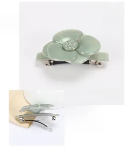 Détail macro d'une pince à cheveux camélia en acétate vert avec strass autrichiens