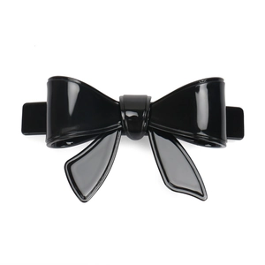 Detailed close-up of a large black acrylic bow hair clip with high-gloss finish