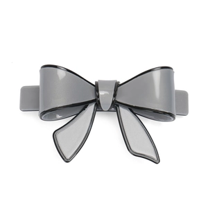 Detail of grey acrylic bow hair clip with black edges and subtle glitter on a white background