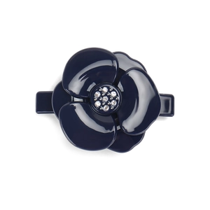 Detailed close-up of dark blue camellia hair clip with crystal center and glossy petals