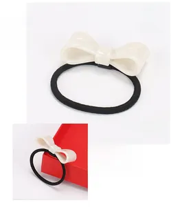 Detailed view of black elastic hair tie with marble texture acetate cream bow decoration