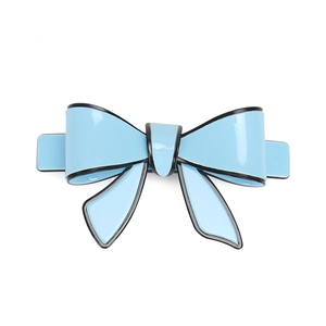 Close-up of blue acrylic bow hair clip with black border and metallic spring fastener