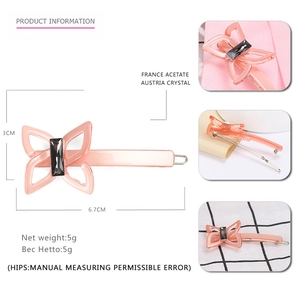 Pink acetate butterfly hair clip with grey crystal accent on a metal anti-slip base