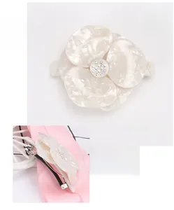 Macro shot of white acetate flower hairpin with sparkling rhinestones and metal clip