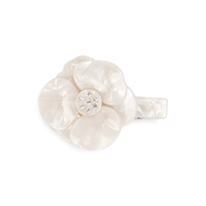 Detail of a white acetate camellia hair clip with sparkling rhinestones and marble finish
