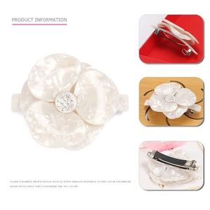 Detailed macro view of acetate floral hair clip with pearl texture and rhinestone center