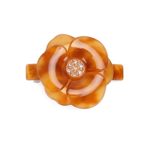 Detail of amber tortoiseshell floral hair clip with crystal center and glossy finish