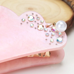 Macro detail of pink cloud hair claw with glitter resin and pearl pendant