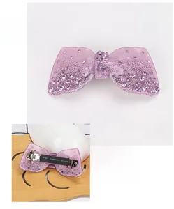 Détail de la barrette à nœud violet en acrylique avec strass brillants et pince à ressort