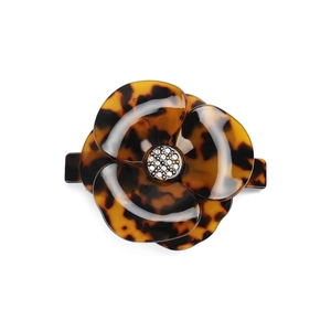 Detailed macro view of acetate flower hair clip with leopard pattern and crystals