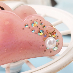 Macro shot of cloud-shaped pink gradient hair claw clip with rhinestones and pearl