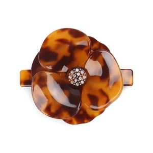 Macro detail of acetate flower hair clip with leopard pattern and crystal center