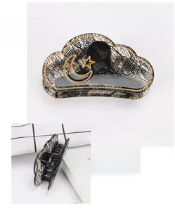 Macro detail of cloud-shaped acrylic hair claw with moon stars and lace pattern