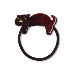 Detail of cute cat acrylic hair tie with dark red marble texture and golden sleepy face