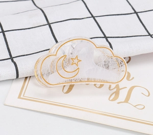 Detail of cloud-shaped transparent hair claw with gold moon star patterns and lace