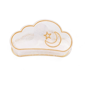 Detail of cloud-shaped hair claw with gold star and moon patterns on white texture