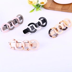 Detail of four acetate tortoiseshell hair clips with linked ring design on white surface
