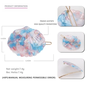 Détail d'une pince à cheveux coquillage en acétate rose et bleu avec strass dorés