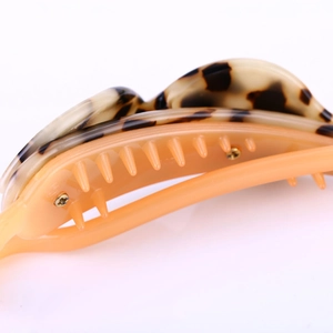 Détail macro d'une pince à cheveux en acétate écaille avec dents orange transparentes