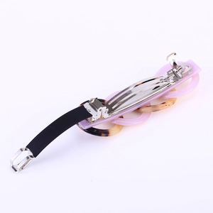 Detail of French acetate hair clip featuring pink and tortoise shell links on black band