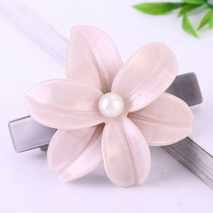 Barrette élégante en acétate avec camélia rose et perle sur un fond clair et doux