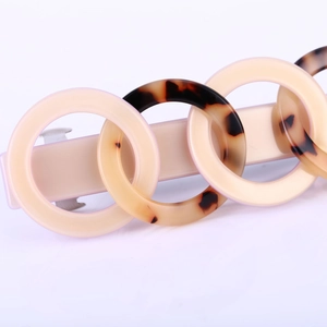 Detail of beige and tortoise acetate linked rings on a metal spring hair clip