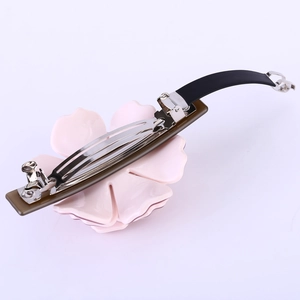 Détail de la pince à cheveux fleur rose en acétate avec boucle en métal argenté