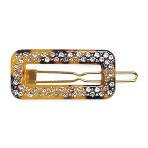 Close-up of rectangle amber hair clip with sparkling white rhinestones on golden clip