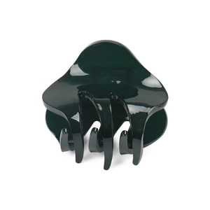 Detail of a large glossy dark green acrylic hair claw clip with multi-tooth design