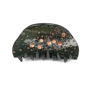 Dettaglio di un grande fermaglio per capelli verde scuro marmorizzato con strass ambra
