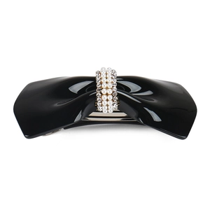 Detailed view of a black resin bow hair clip with faux pearl and rhinestone accents