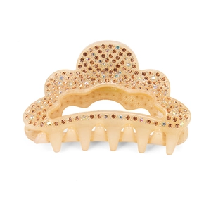 Détail d'une pince à cheveux beige en acrylique ornée de strass ambrés scintillants