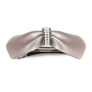 Detail of elegant beige bow hair clip with faux pearls and dark grey rhinestones