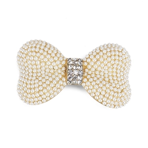 Barrette à cheveux nœud doré avec perles et strass brillants sur un fond blanc neutre