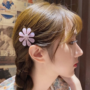 Pale purple acetate flower hair clip with rhinestones worn by a model in warm light