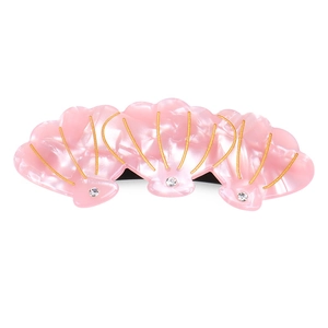 Détail de la pince à cheveux coquillage rose avec lignes dorées et accents de strass
