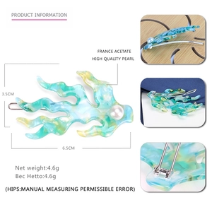 Dettaglio macro della clip per capelli in acetato corallo con perla decorativa