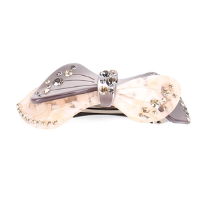 Detailed view of the bow-shaped hair clip featuring marble patterns and sparkling crystals