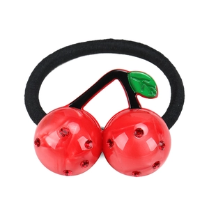 Close-up of a black elastic hair tie with a sparkling red rhinestone cherry and green leaf