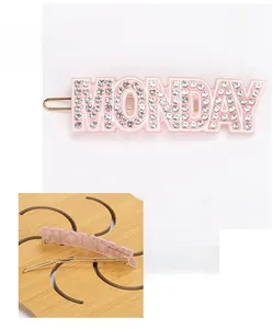 Vue détaillée avant et arrière de la pince à cheveux en acétate rose avec lettres MONDAY