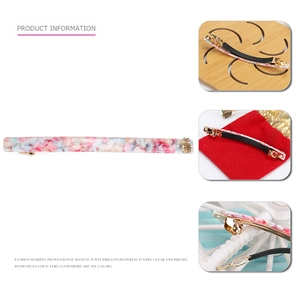 Detail of floral acetate hair clip with gold pineapple charm and spring clip structure